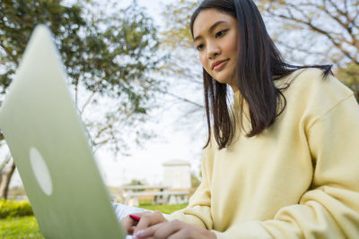 Young woman using mobile phone in park