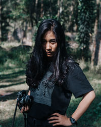 Beautiful young woman standing against trees in forest