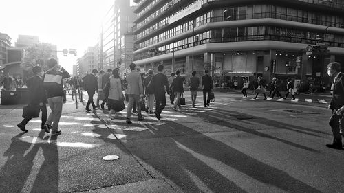 People walking on modern city against sky