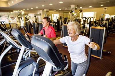 Senior man and mature woman on step machine in fitness gym