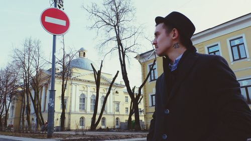 Man smoking cigarette street against buildings