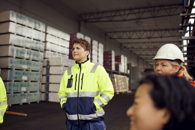 Female engineer in reflective clothing standing with hands in pockets at factory