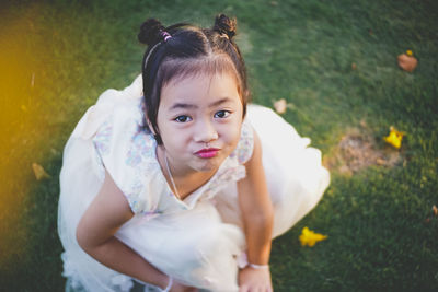 High angle portrait of cute girl puckering on field at park