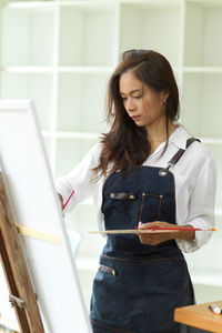 Young woman looking away while standing on wall