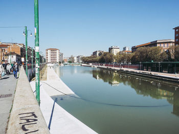 River by buildings against clear blue sky