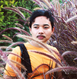 Portrait of young man standing against plants