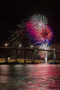 Illuminated firework display against sky at night