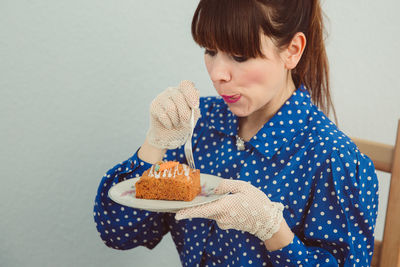 Close-up of woman holding ice cream against white background