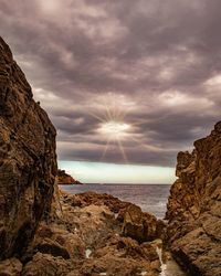 Rock formation by sea against sky