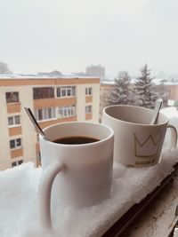Close-up of coffee cup on table against window during winter