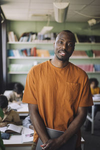 Teacher in orange t-shirt standing in classroom