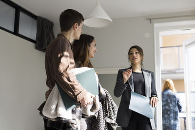 Low angle view of female real estate agent assisting clients during house visit