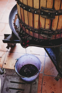 High angle view of wine filling in bucket from cask at factory