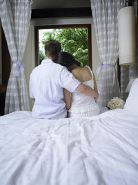Rear view of couple relaxing on bed