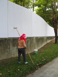 Rear view of woman painting fence