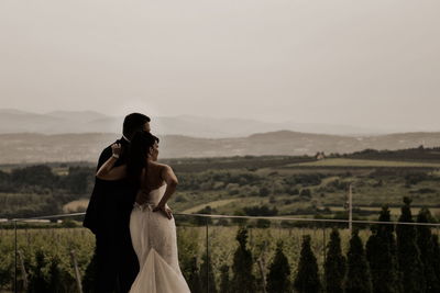 Couple standing on railing against sky