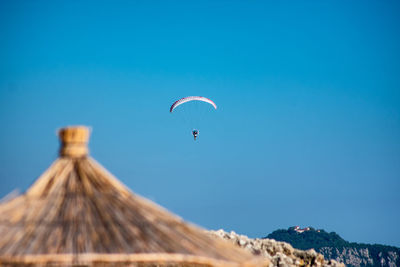 Low angle view of person paragliding against blue sky