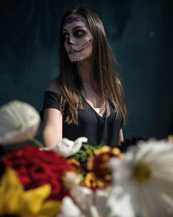 Close-up of flowers against thoughtful woman with spooky halloween make-up standing outdoors