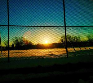 Chainlink fence on landscape at sunset