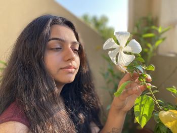 Portrait of beautiful woman holding red flowering plant