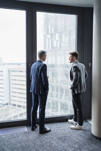 Business people discussing while standing by window in office