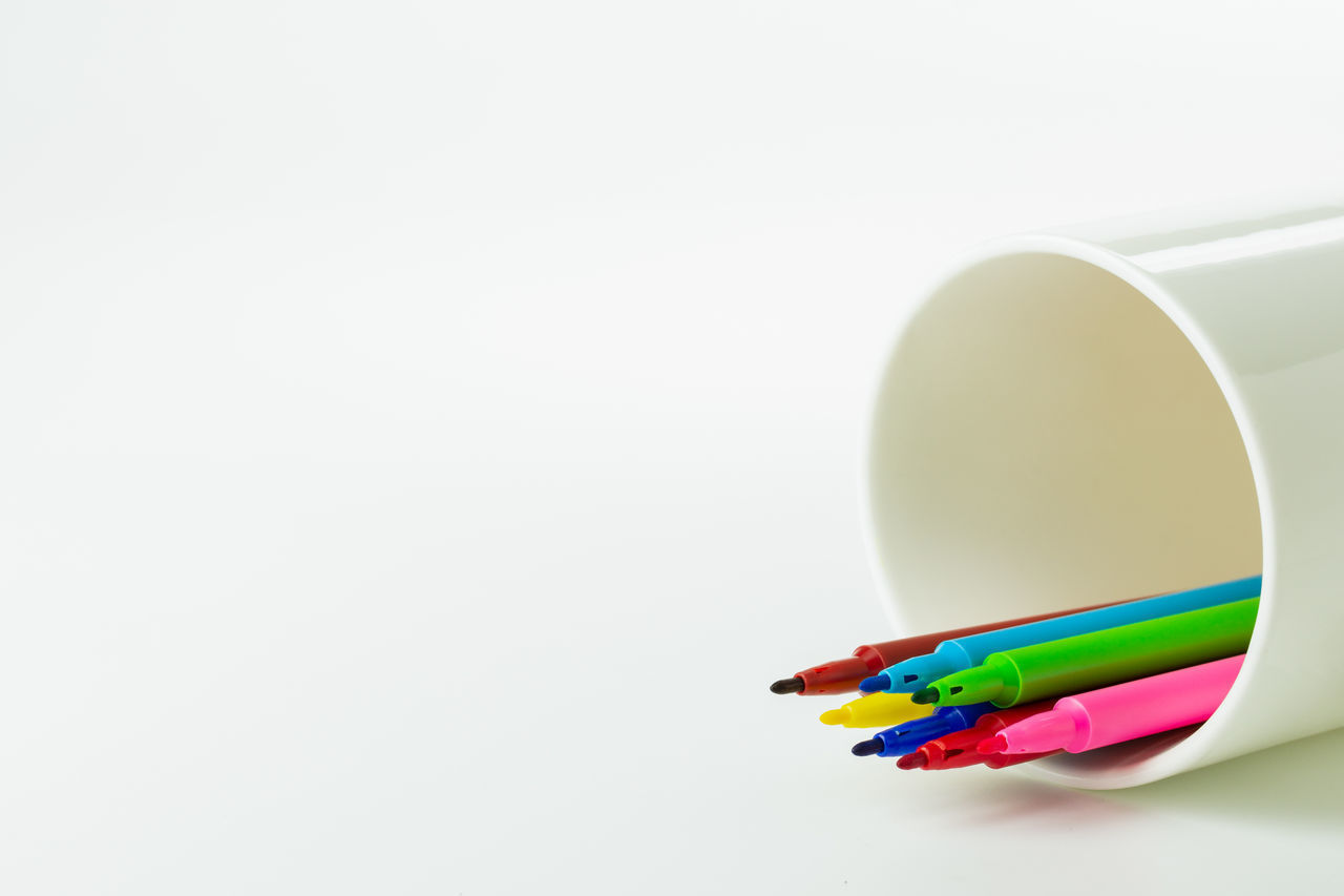 CLOSE-UP OF COLORED PENCILS OVER WHITE BACKGROUND