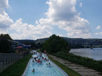 People on bridge over river against sky