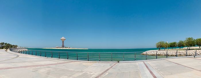 View of swimming pool by sea against clear blue sky