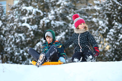 Winter portrait of children with a plastic sled sliding on a snowy slope 