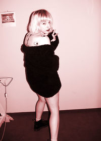 Portrait of young woman standing on wall