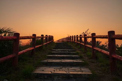 Footpath against clear sky during sunset