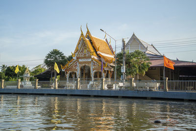 Buildings by river against clear sky