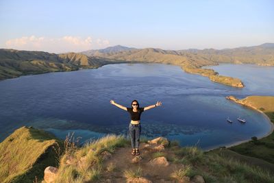 Woman standing on lake by mountain against sky