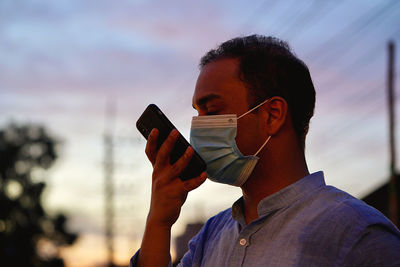 Man wearing ask talking on phone during sunset