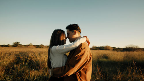 Romantic couple hugging in a field at sunset light
