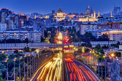 Light trails on city street amidst buildings at night