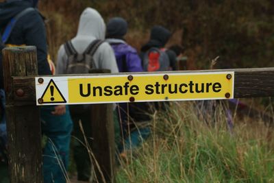 Rear view of people walking in forest with signboard on foreground