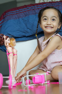 Cute girl playing with doll while sitting on floor at home