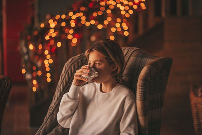 Portrait of candid authentic smiling handsome boy teenager using mobile phone at xmas home interior