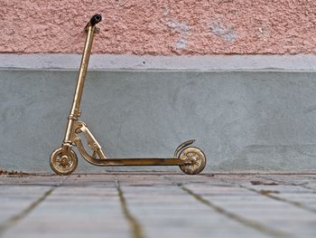 Bicycle parked on footpath against wall