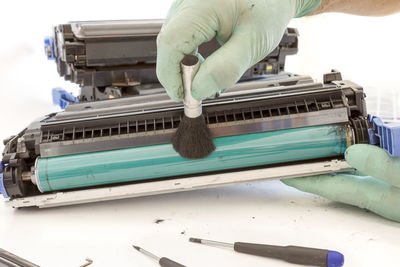 Cropped image of person cleaning machinery at table against white background