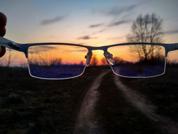 Close-up of sunglasses against sky during sunset