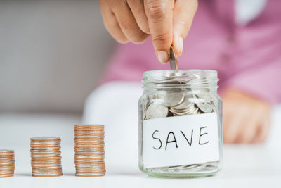 Close-up of hand holding coins in jar