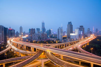 High angle view of light trails on road amidst buildings in city against sky