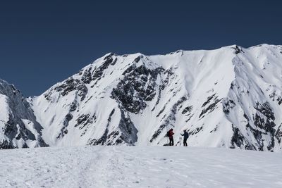 People on snowcapped mountain against sky