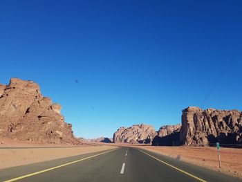 Road amidst rocks against blue sky