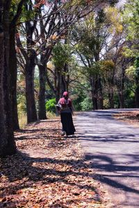 Rear view of woman with umbrella walking on tree trunk