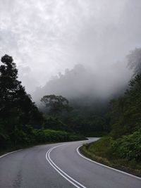 Road by trees against sky