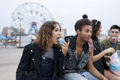 Friends eating cotton candy at an amusement park