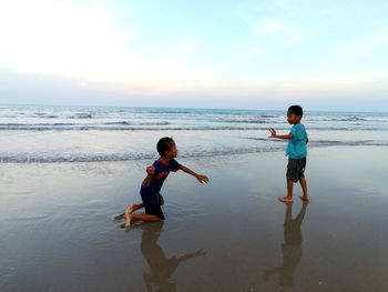 Full length of friends on beach against sky